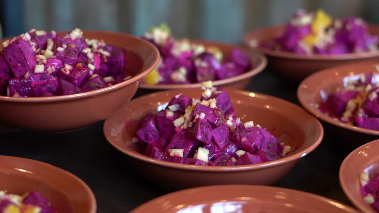 Bowls of vibrant purple beet salad topped with chopped garlic or onions, close up shot