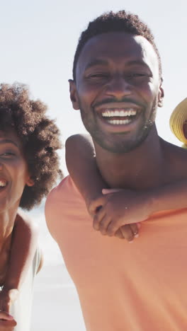 portrait of smiling african american family embracing on sunny beach