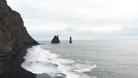 playa de arena negra de reynisfjara y pilas marinas de basalto en el océano, islandia