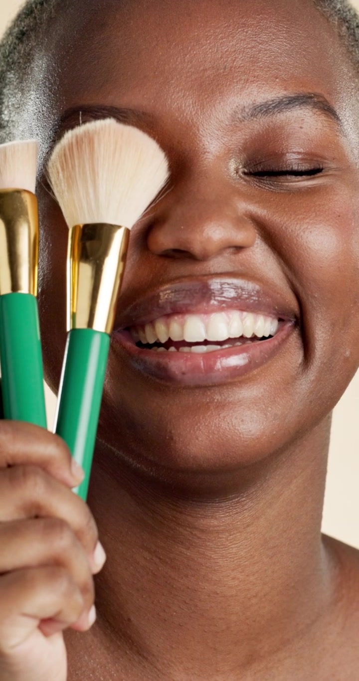Young Woman Holding Makeup Brushes and Smiling