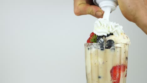 slider shot of whipped cream being added to a fruity ice cream