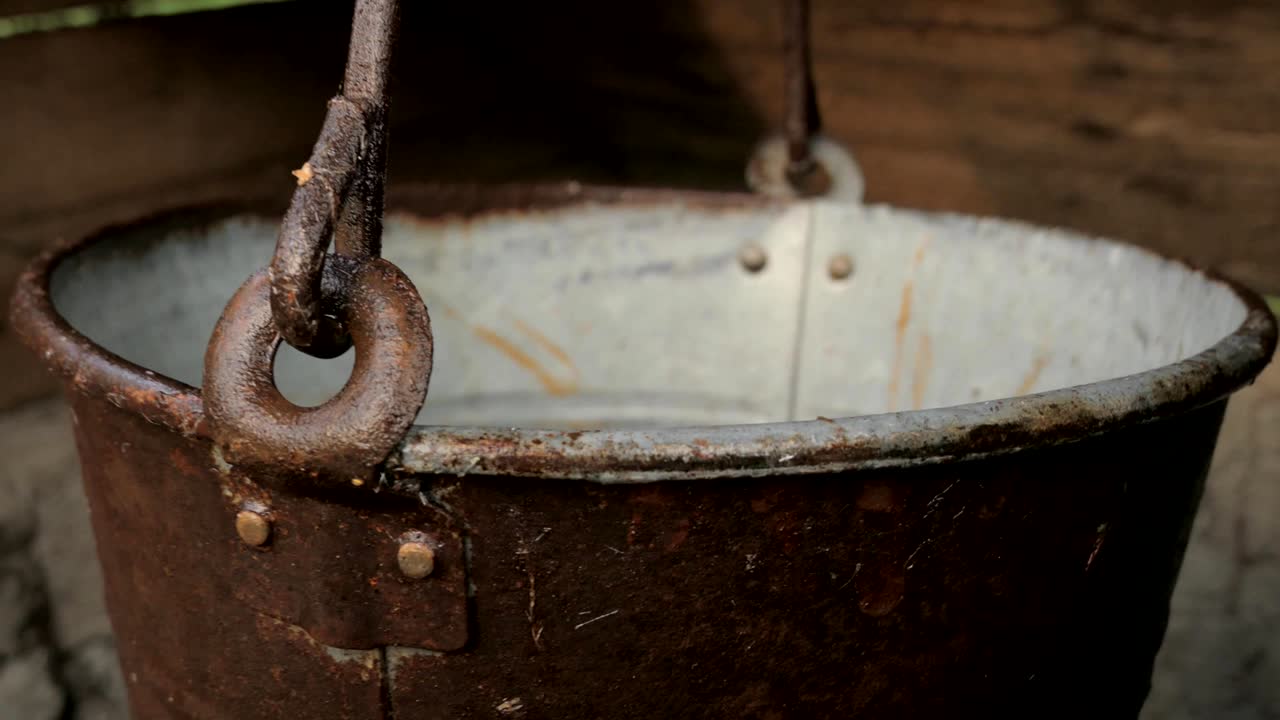 un cubo de metal vacío colgando en un pozo rural