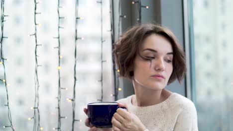 woman enjoying a warm drink by the window