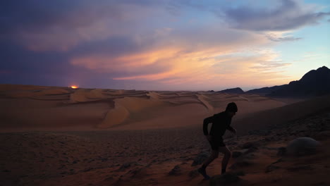 person climbing a sand dune at sunset in a vast desert landscape