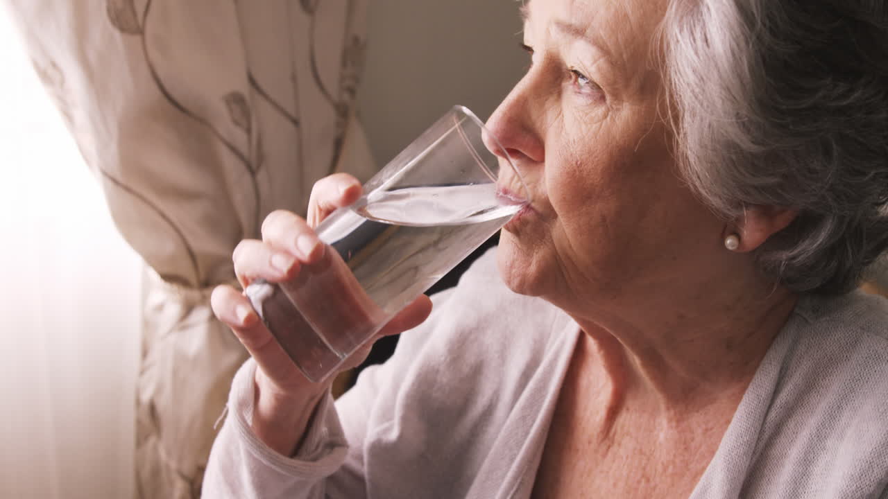 mujer anciana enferma tomando pastillas con agua