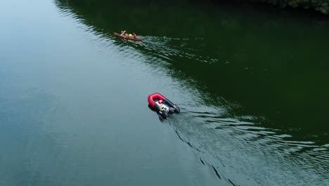 a red motorboat leading the canoe