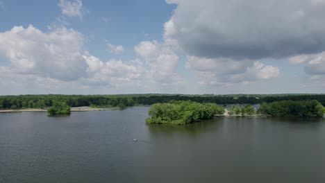 Eine-Drohnenaufnahme-Eines-Wunderschönen-Seereservoirs-Mit-Dichtem-Wald-Vor-Weißen-Wolken-Am-Blauen-Himmel