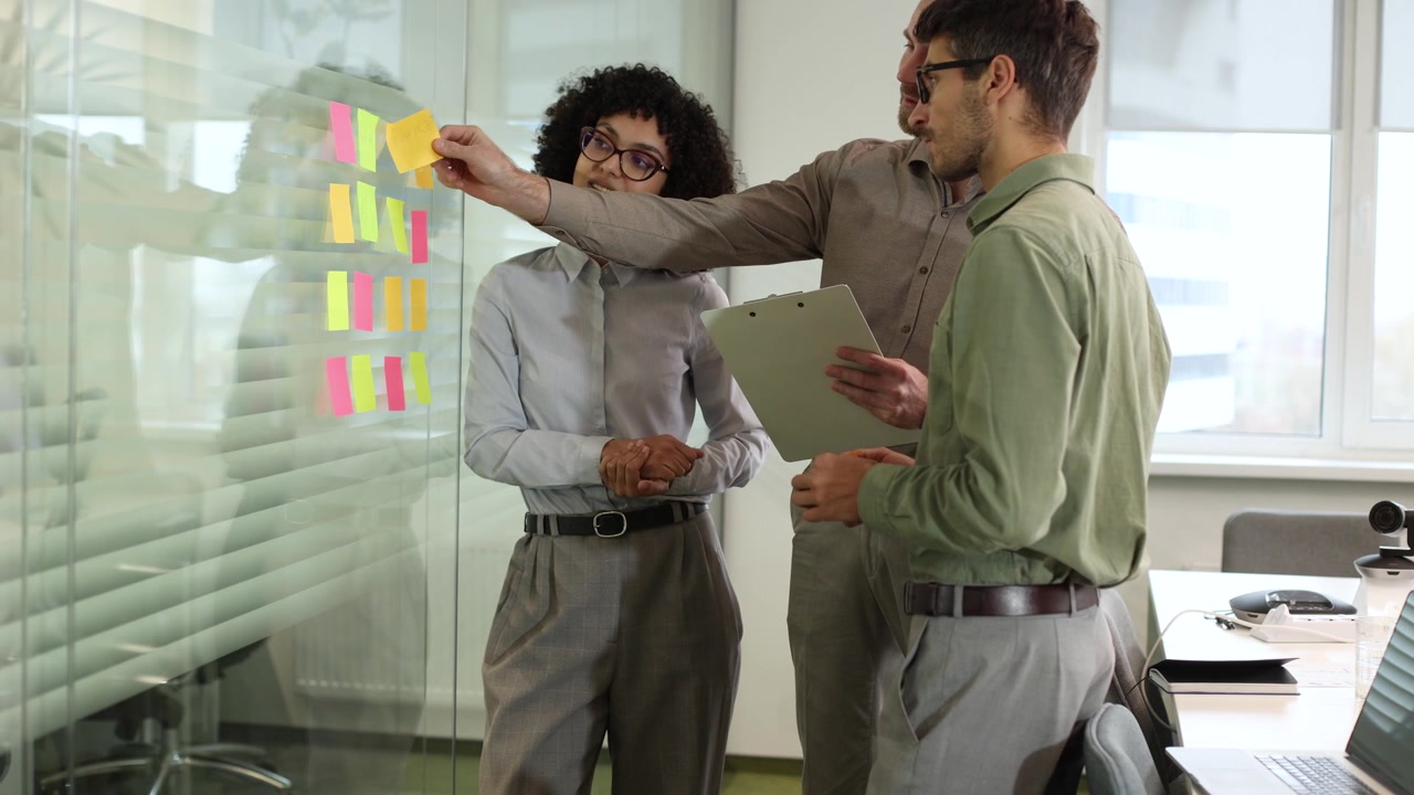 Equipe de negócios diversificada debatendo ideias em parede de vidro em escritório moderno