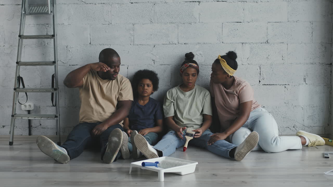 Family taking a break from painting a wall