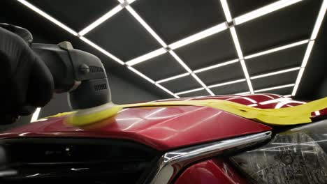 worker polish a red car. car detailing - men are using machinery car polishers maintenance to remove marks repair according to the surface of the car's paint before continuing to coat the ceramic