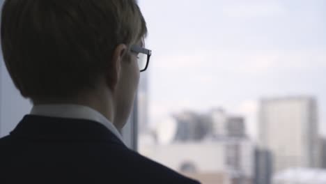 man looking out of window at city