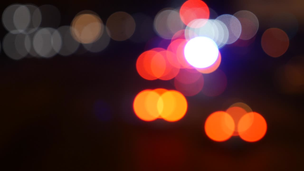 hermoso bokeh brillante en el fondo oscuro borroso por la noche. el redondo bokeh colorido brilla de las luces de los coches en la calle de la ciudad. fuera de foco con borroso. luces de la ciudad sin enfoque. bokeh de tráfico. concepto abstracto