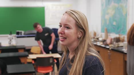 young college student chatting in her geology classroom while other students are studying