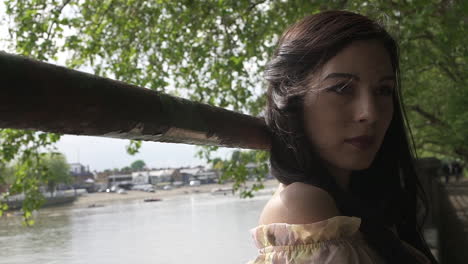 Retrato-De-Una-Atractiva-Modelo-Latina-Posando-Junto-Al-Río-Támesis-En-Londres,-Mirando-A-La-Cámara-Con-Un-Vestido-Floral