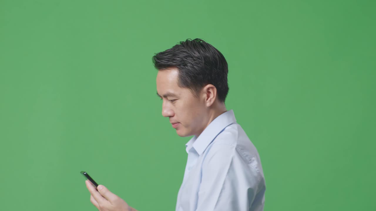스튜디오에서 녹색 화면 배경에서 는 동안 휴대전화를 사용하는 아시아 사업가의 측면 뷰 클로즈업
