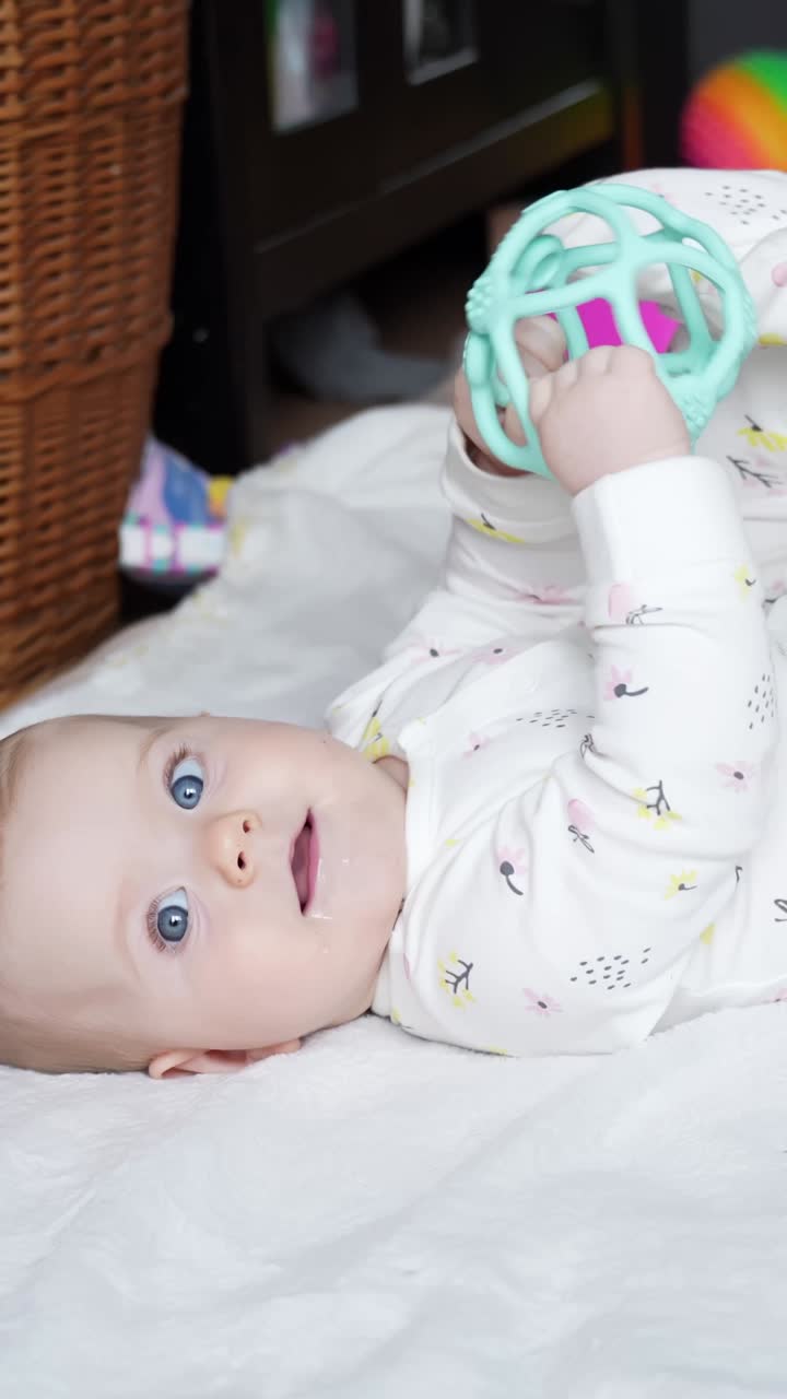 Happy baby girl with deep blue eyes enjoying toys, vertical view