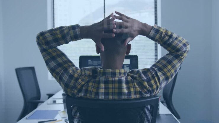 Software developer typing on keys and pausing for posture relief, stretching overhead, leaning back