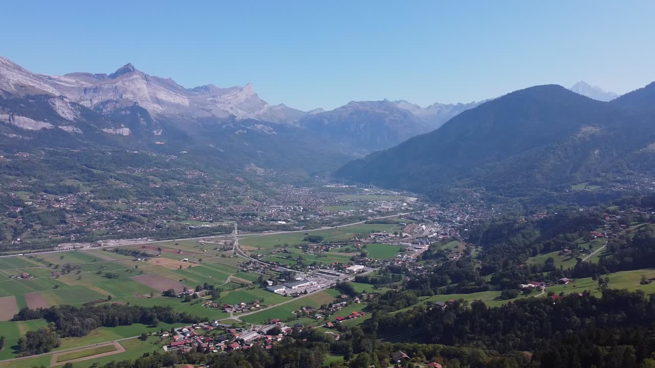 panorámica aérea desde un valle poblado hasta una cadena montañosa