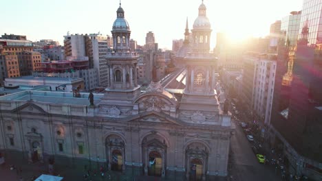 Aerial-view-towards-Metropolitan-Cathedral-of-Santiago-with-sunset-behind-bell-tower-and-Plaza-De-Armas-cityscape