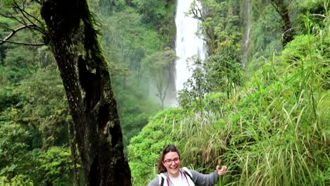 young female raising arms happily as she reached materuni waterfall