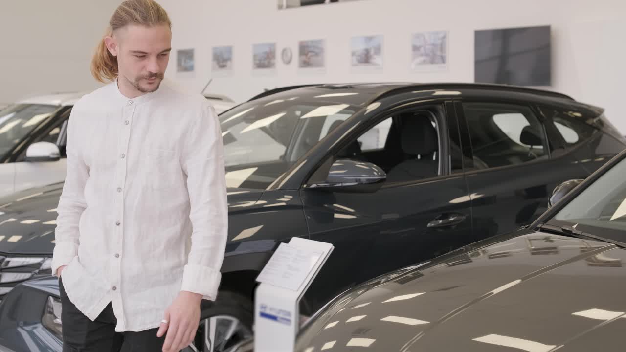 feliz barba de pelo largo cliente masculino en la sala de exhibición de vehículos, persona masculina que compra transporte, negocio de concesionarios de automóviles. hombre mirando el coche nuevo. consumidor en concesionario de automóviles, hombre de negocios eligiendo un coche.