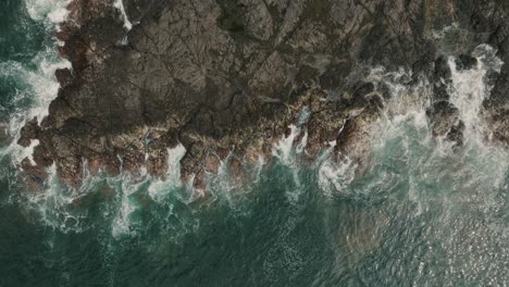 top down view of ocean waves crashing on rocky shore of beach in guanacaste, costa rica - aerial drone shot