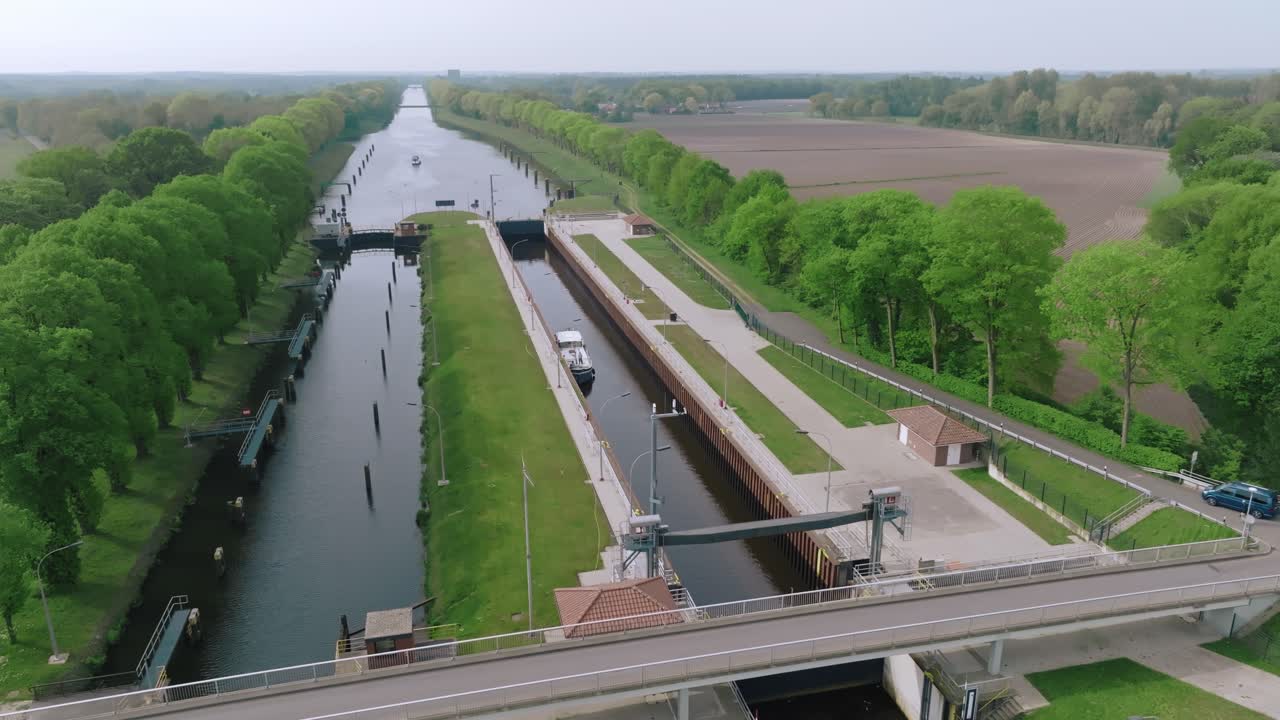 Semi orbit movement showing a barge entering Doerpen Lock, with structured canal design and parallel tree lines under soft daylight.