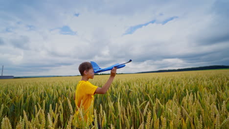happy boy plays outdoors. cute child holds toy play and turns around joyfully. kid on yellow field playing alone.