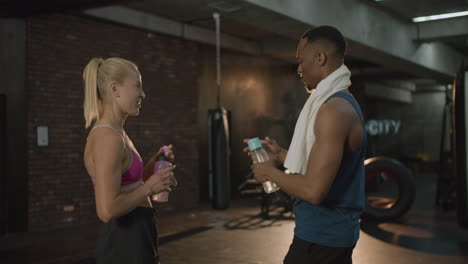 Side-view-of-caucasian-female-monitor-and-an-athletic-african-american-man-in-the-gym.