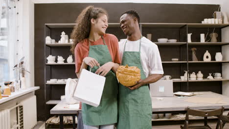 two co workers at a pottery store posing in front of the camera while smiling and hugging each other