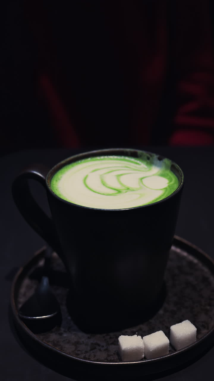 Close up of a matcha latte on a tray at a cafe. Vertical