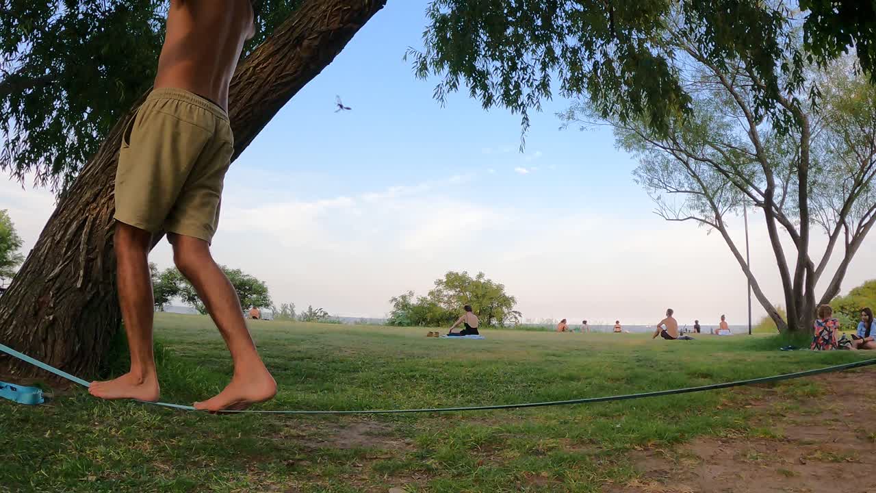 Lateral shot of adult male legs balancing on slack line at park outdoors