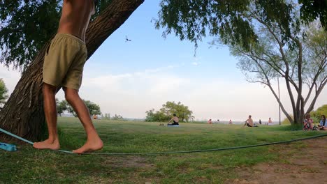 Seitliche-Aufnahme-Erwachsener-Männlicher-Beine,-Die-Auf-Einer-Slackline-Im-Park-Im-Freien-Balancieren