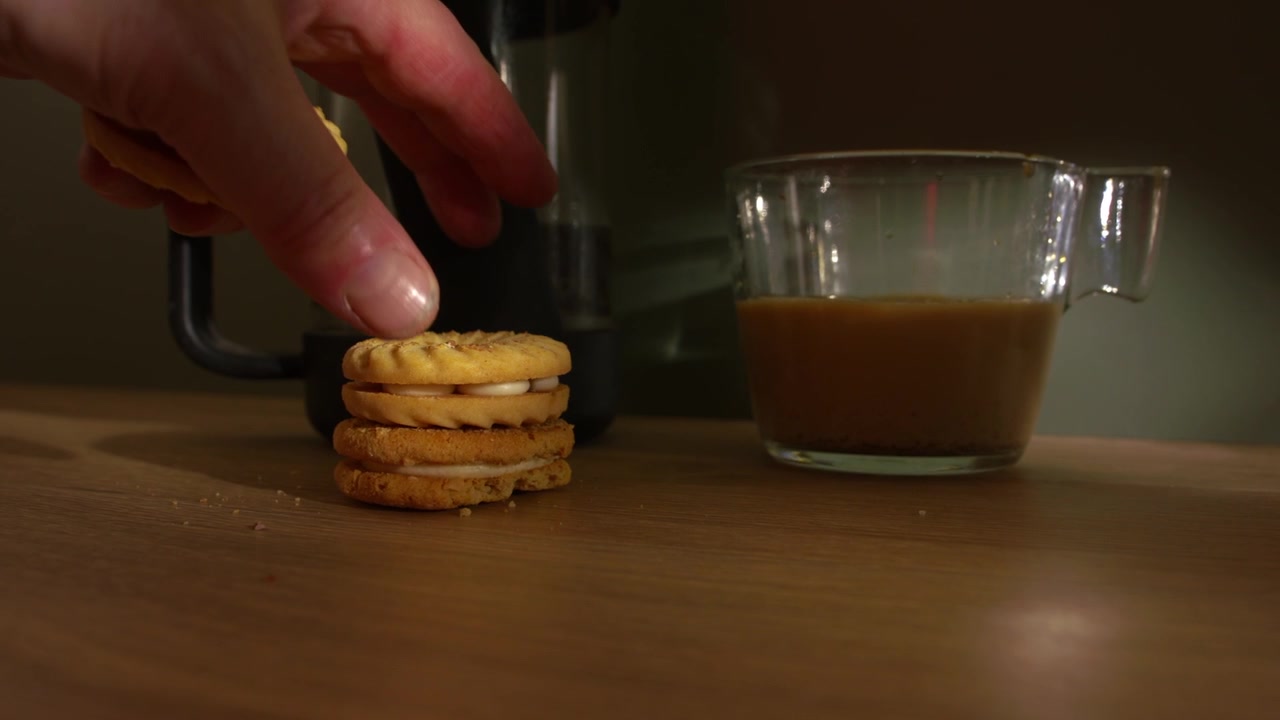 Hand with coffee getting handful of cookies medium zoom shot selective focus