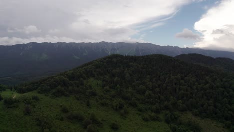 Lush-green-mountain-landscape-under-a-cloudy-sky,-aerial-view