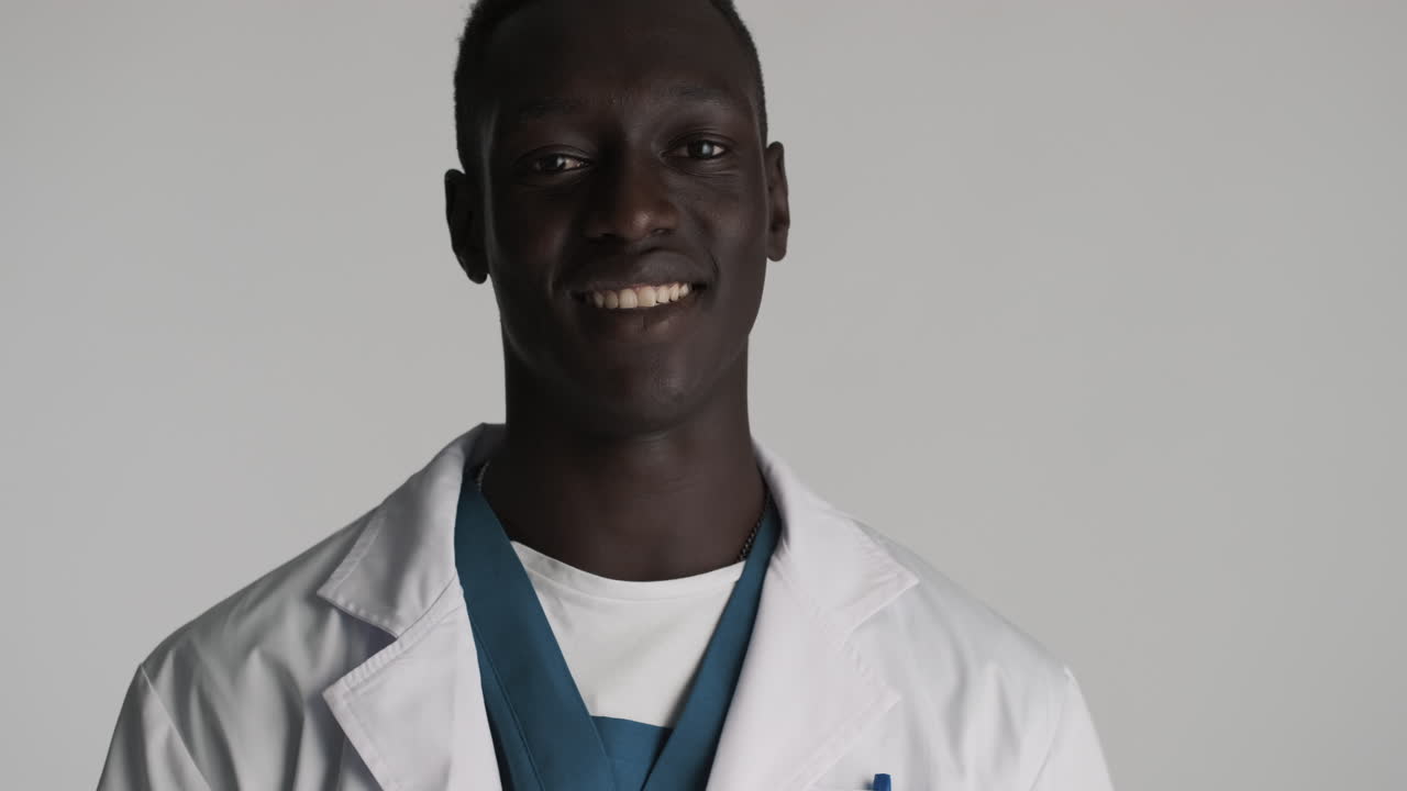 feliz médico afroamericano en el fondo gris.