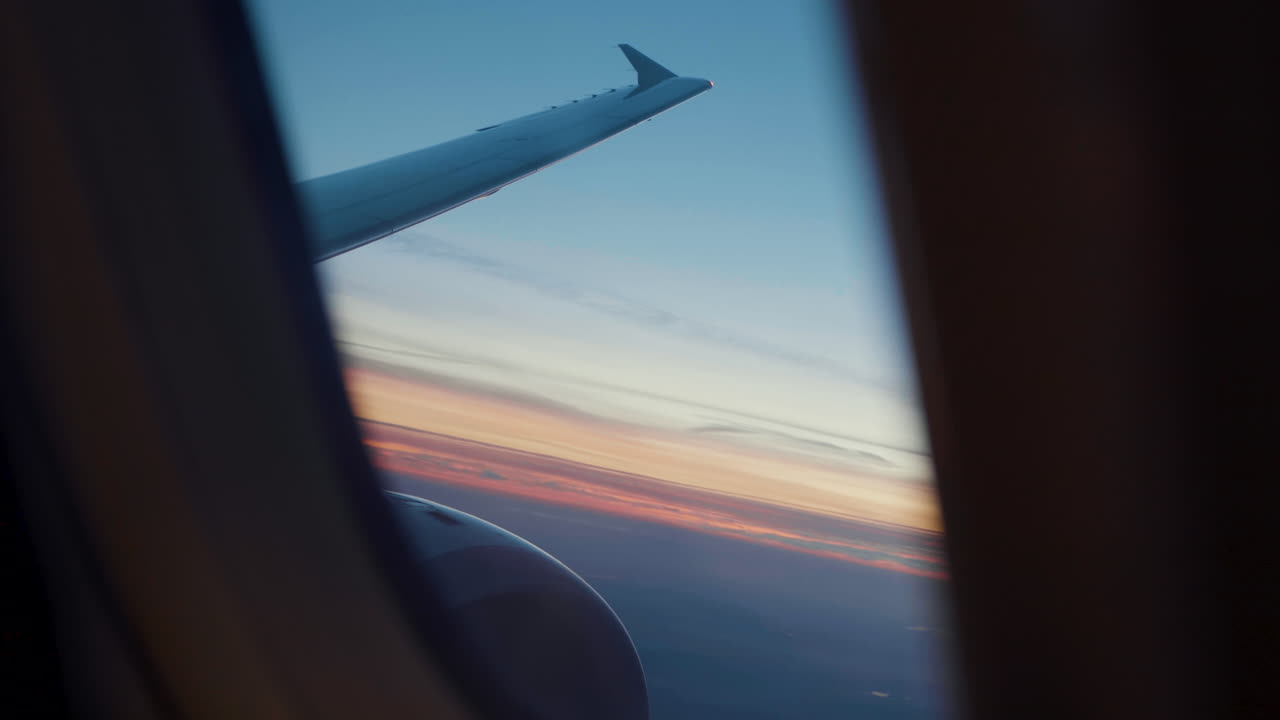 Beautiful Sunset above the clouds view from Airplane Window with wing