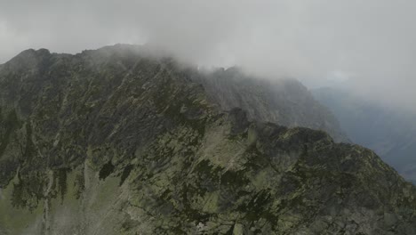 massive clouds cover the mountain range near at skok waterfall and the high tatras in slovakia - aerial shot