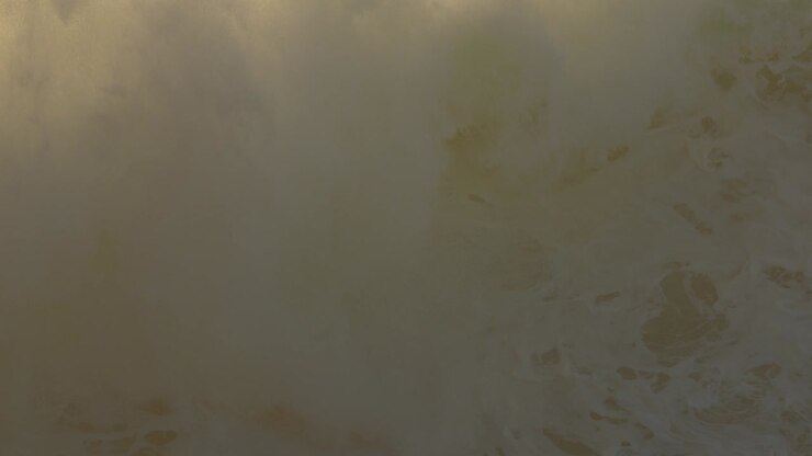 Big wave breaking in Nazare beach with spray making a haze in background