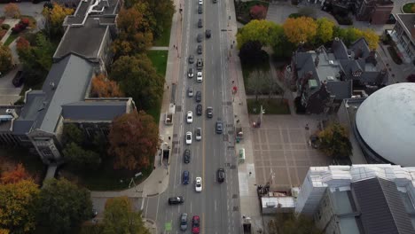 wide aerial of city street traffic surrounded by buildings and large colorful urban park