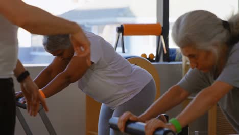 entrenador asistiendo a mujeres mayores mientras realizan yoga 4k
