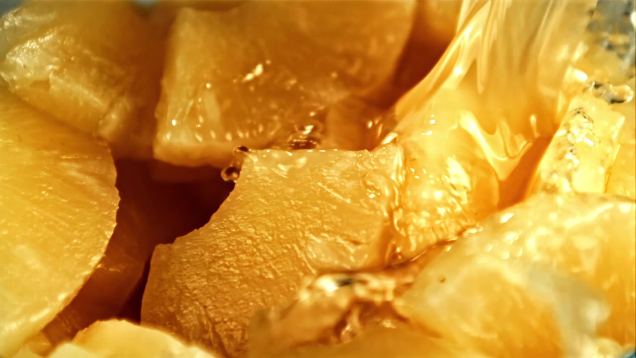 Liquido versato al rallentatore su pezzi di ananas fresco