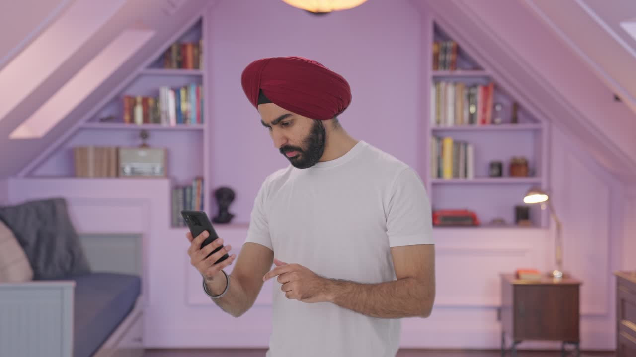 Uomo indiano Sikh che scorre il telefono