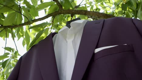 a fragment of the groom's jacket and shirt hanging in a garden