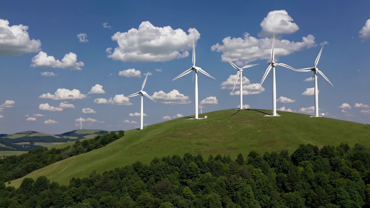Video showcasing wind turbines on a lush green hill under a blue sky with clouds