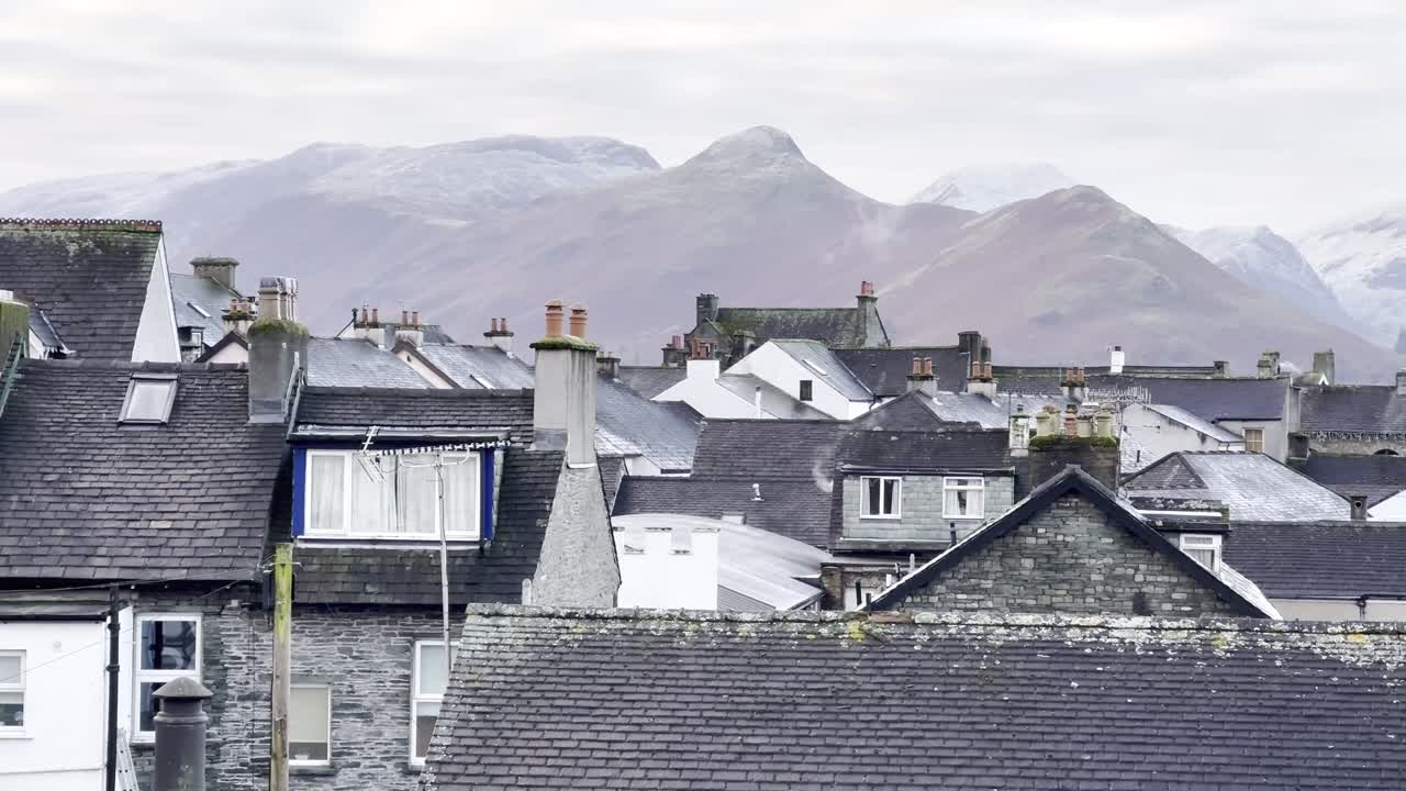 View of iconic fell Catbells perched above rooftops of Keswick town on a snowy winter's morning - Lake District, UK