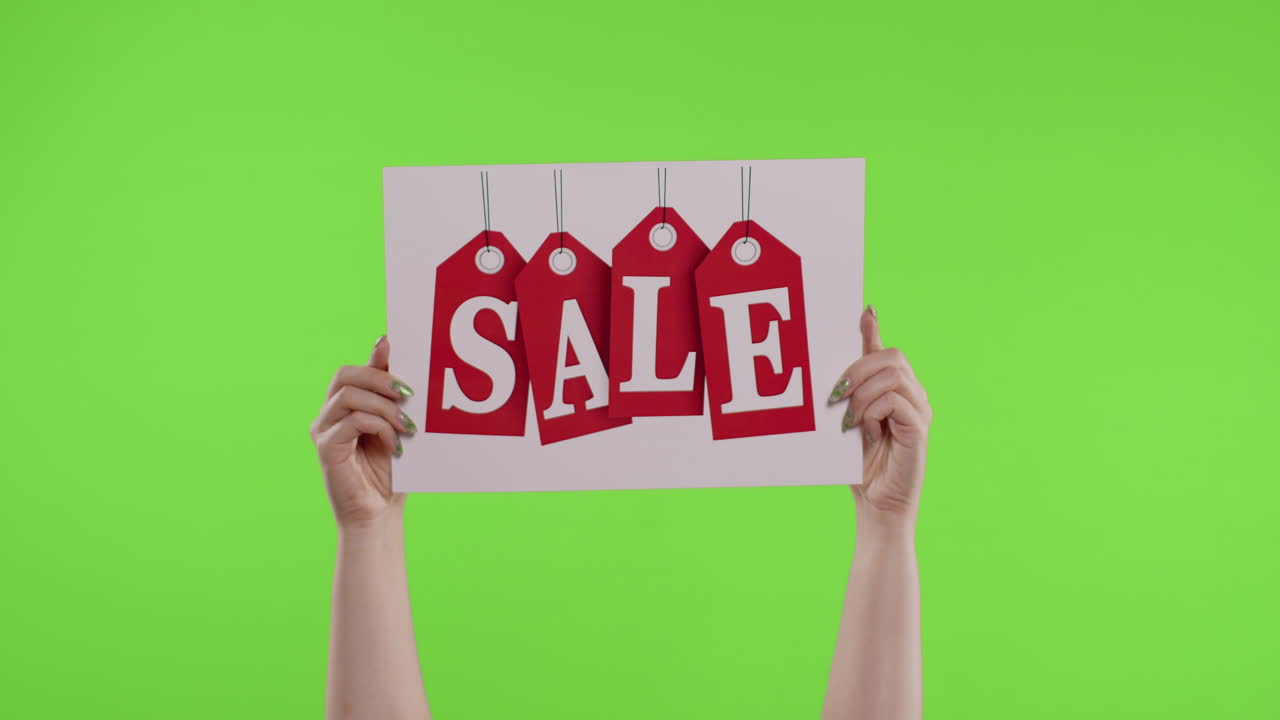 Reklameinskription med ordet "Udsalg" på et stykke papir i kvindes hænder på chroma key. Slowmotion