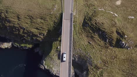 tracking drone shot of a car crossing the scalpay island bridge, near the isle of harris on the outer hebrides of scotland