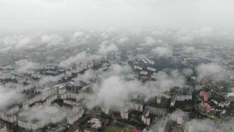 вид с воздуха на городской пейзаж сквозь медленно спускающиеся облака