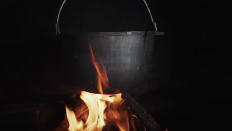 una cuba de hierro fundido de caldo hirviendo cuelga en una estufa de leña sobre un fuego abierto 1